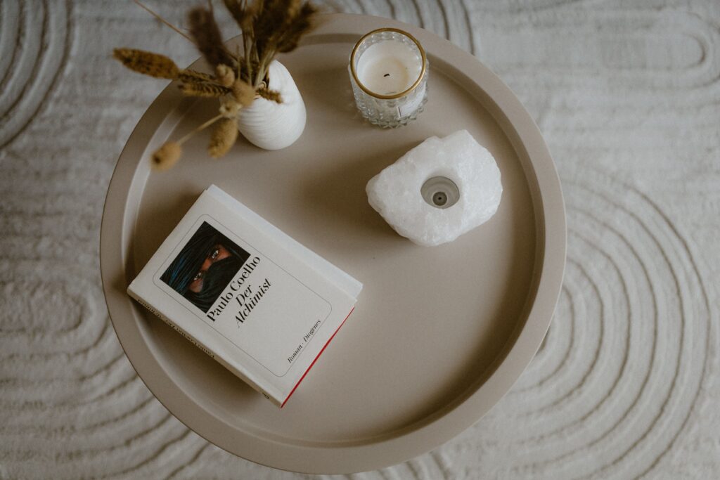 A minimalist tabletop scene featuring a book, a candle, and decor, creating a cozy atmosphere.